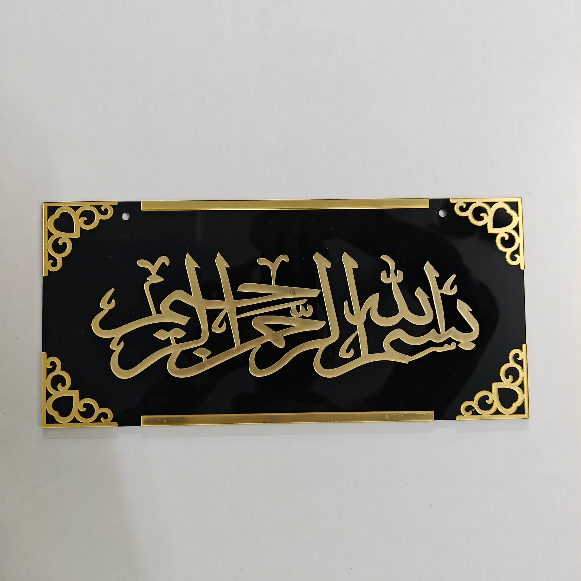 Decorative panel with gold Arabic calligraphy on a black background